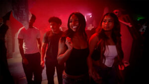 Two women and two men walking through a red lit room